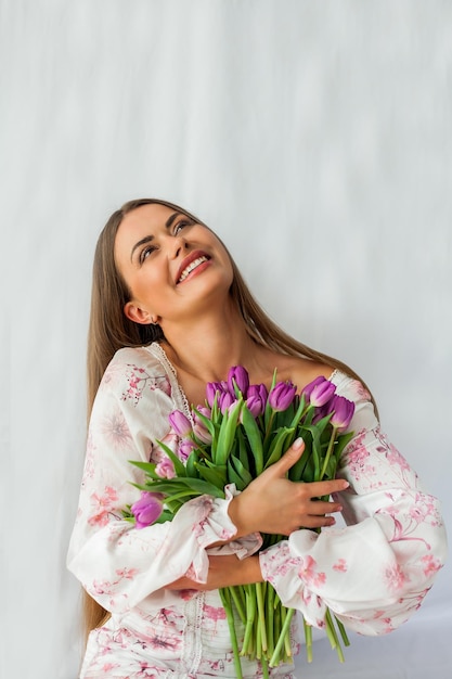 A woman in a kimono holds a bouquet of tulips.