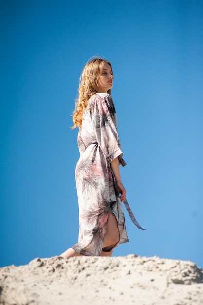 A woman in a kimono stands on a stone wall.