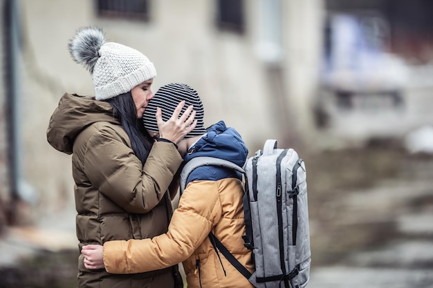 Woman kisses her boy on forehead outdoors as they both stay in the war zone after russia attacked ukraine