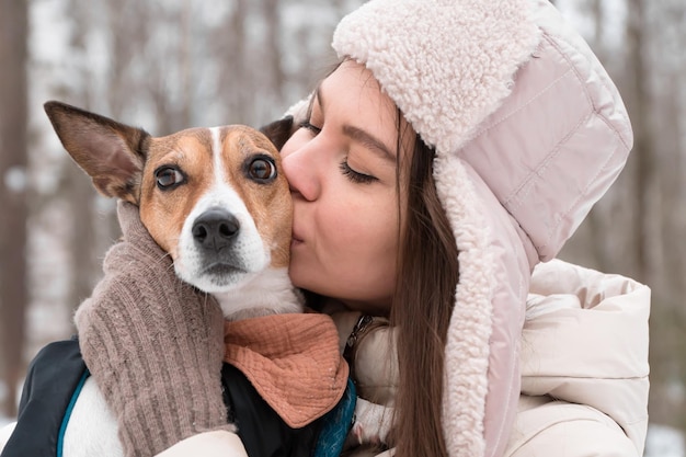 冬の公園を歩いている犬にキスをする女性