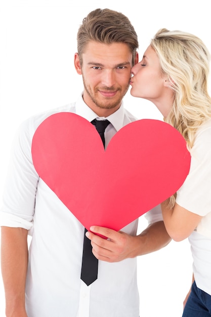 Woman kissing man as he holds heart