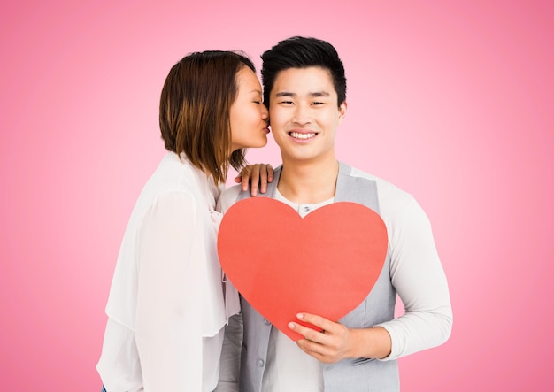 Woman kissing man while holding heart