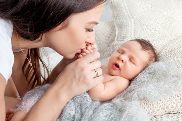 生まれたばかりの赤ちゃんの手にキスする女性