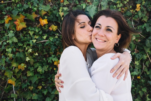 Woman kissing woman in garden