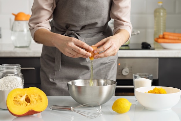 A woman in the kitchen breaks a chicken egg into a bowl. Cooking.