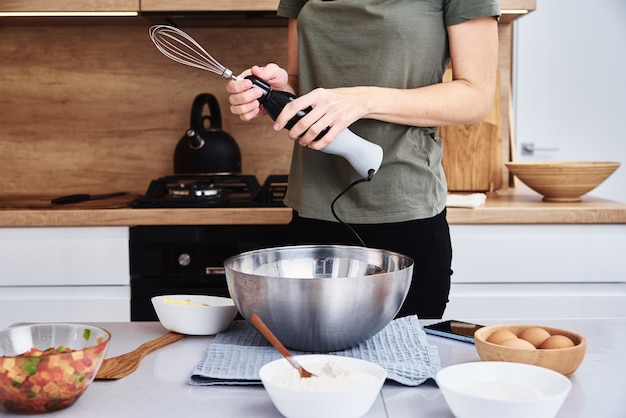 Woman in the kitchen cooking a cake. Hands beat the dough with an electric mixer