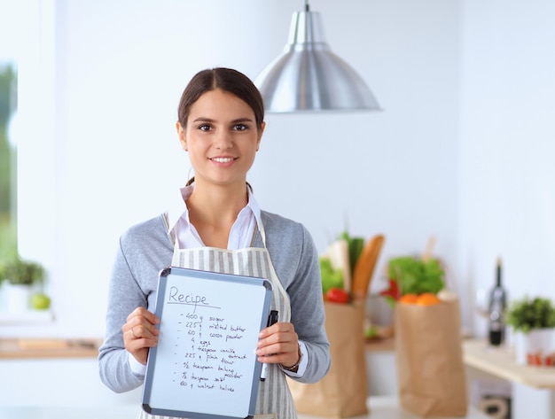 Woman in the kitchen at home standing near desk with folder