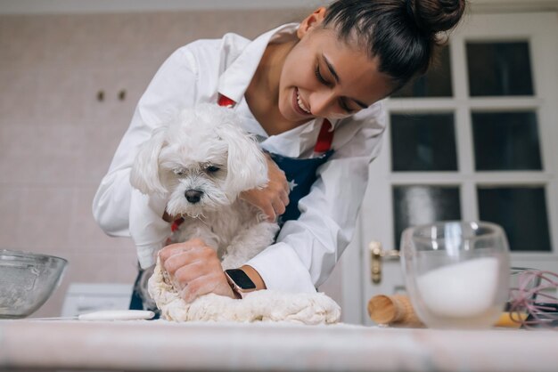 Woman in the kitchen kneads the dough with her dog