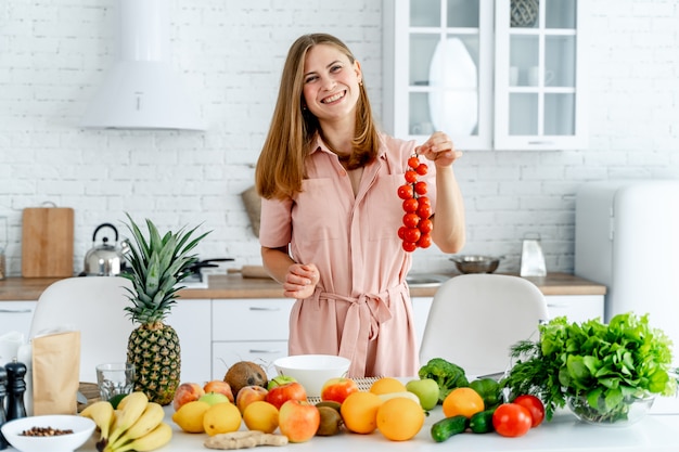 Woman in kitchen ready to prepare meal with vegetables and fruits. 