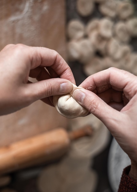 キッチンの女性が生地から餃子を作り、肉を詰めておいしい自家製料理を作ります