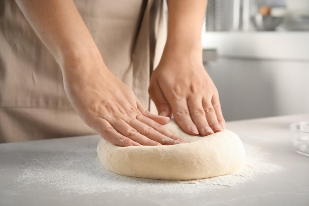 Woman kneading dough for pastry on table