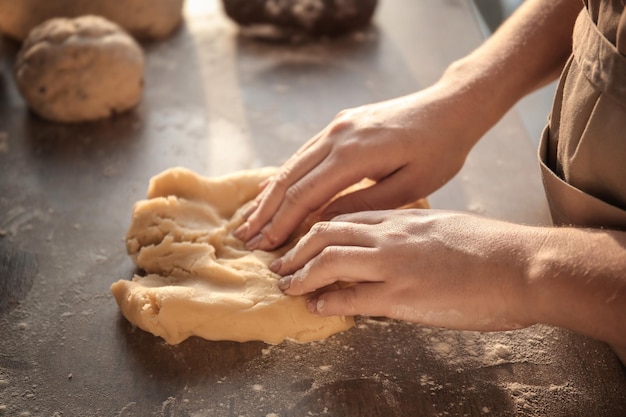 Woman kneading dough on table closeup