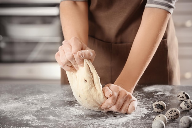 Woman kneading dough on table