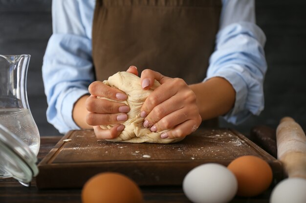 Woman kneading flour in kitchen, closeup