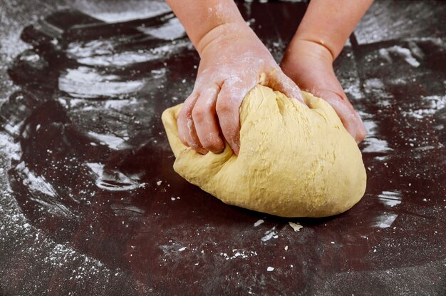 Woman kneading with hands dough for making bread