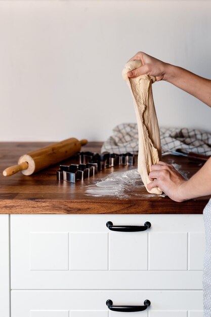 Foto la donna impasta la pasta. biscotti allo zenzero sulla tavola di legno. cucina casalinga accogliente. cottura casalinga.