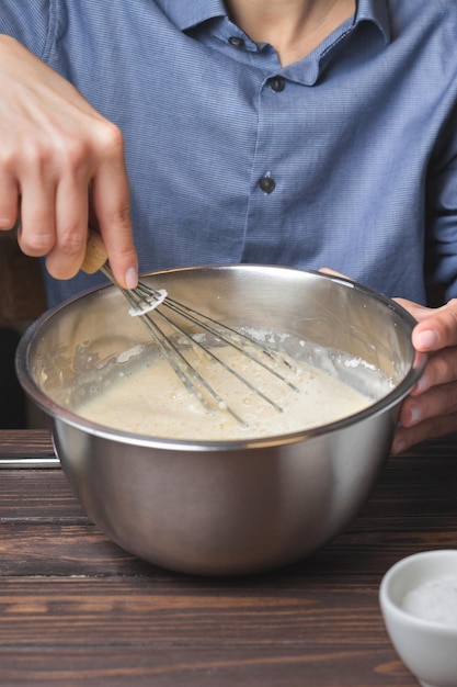 Woman kneads dough in a metal bowl Preparation of dough for baking pancakes Selective focus