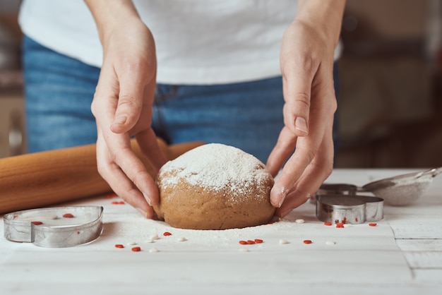 Woman kneads dough with hands in kitchen