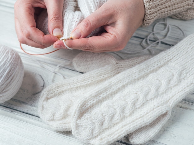 Woman knits winter warm clothes closeup