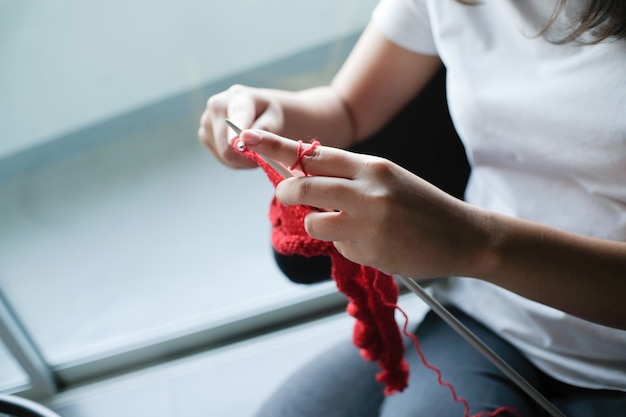 La donna lavora a maglia la sciarpa del cerchio di lana, ferri da maglia.