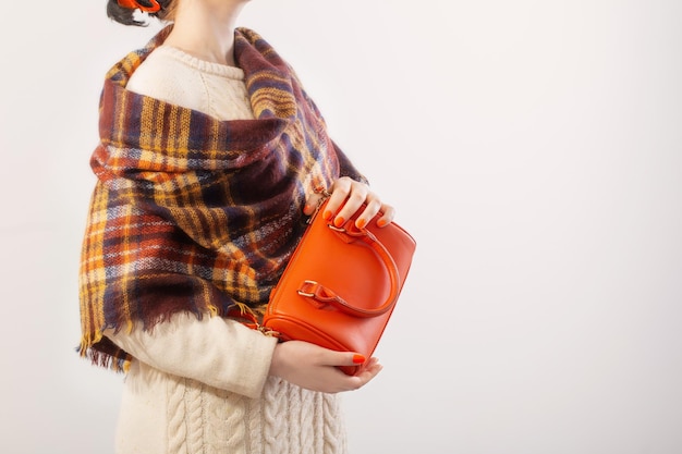 Woman in knitted sweater with orange handbag on white background