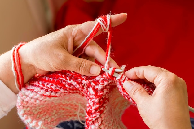 Woman knitting needles web of light wool yarn. Knitting needles.