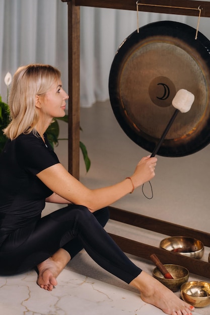 A woman knocks a mallet with a hammer on a gong A gong and a hand beater for the gong