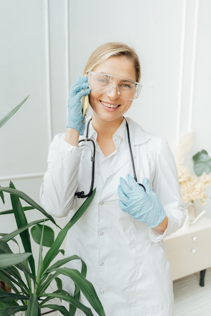 A woman in a lab coat talks on a phone.