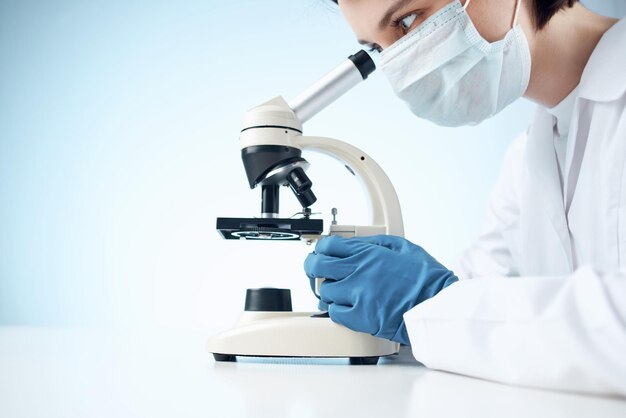 Woman in laboratory looking through microscope closeup biotechnology science