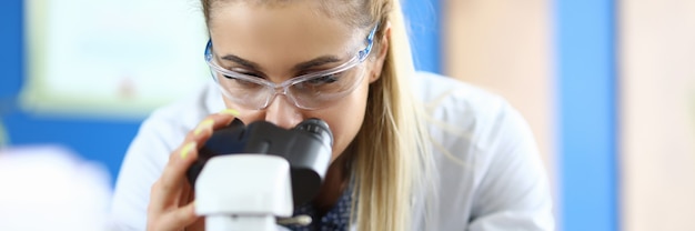 La donna in laboratorio guarda attraverso il microscopio