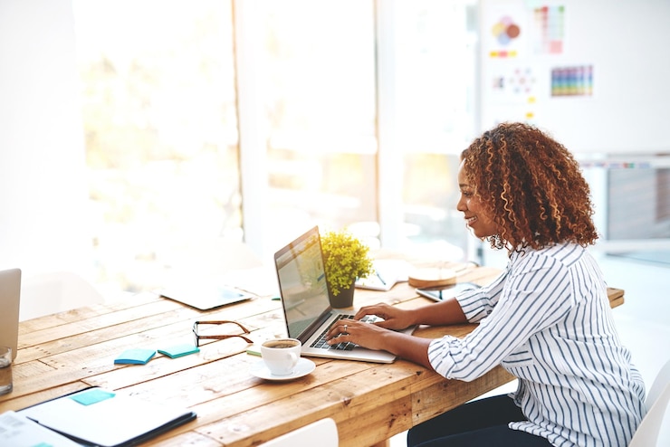 Photo woman laptop and typing in office for social media post communication or online news and email female person technology and writing message for internet research web browsing or networking