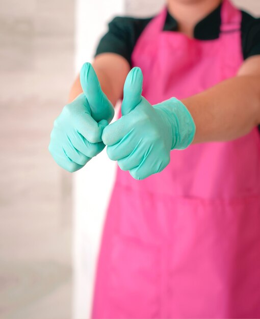 woman in latex gloves and pink apron holding thumbs up as a hope symbol Ok hope win concept