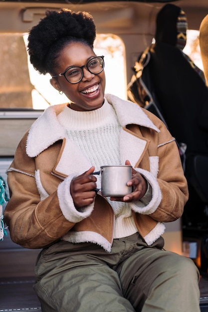 Woman laughing in a camper van with a cup of coffee