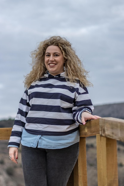 A woman laughing loudly outdoors against a background of cloudy sky