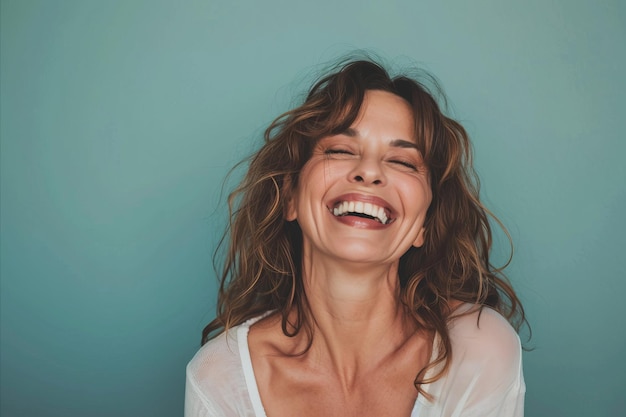 A woman laughing and smiling in front of a blue background