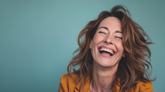 Photo a woman laughing and smiling in front of a blue background