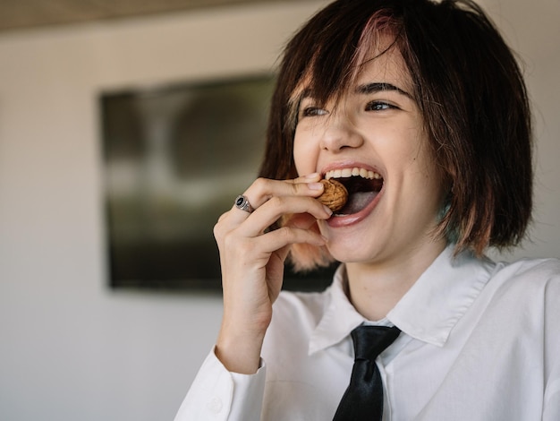 Woman laughing while trying to bite a walnut with her mouth, horizontal blurred background