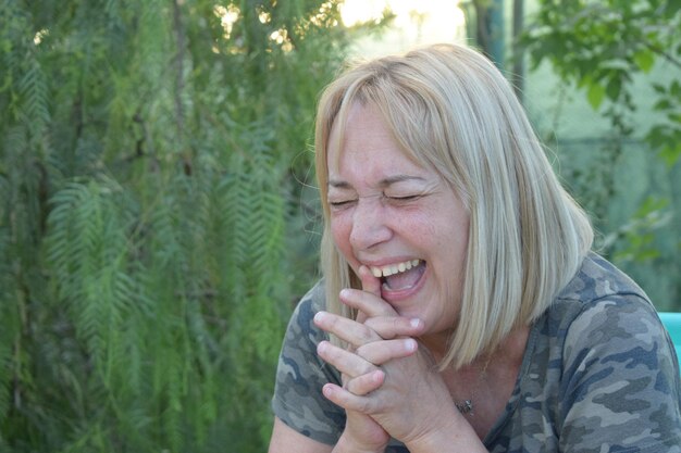 Woman laughing with her eyes closed in a square with a green background