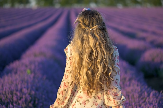 Woman in lavender field at sunset wearing summer dress