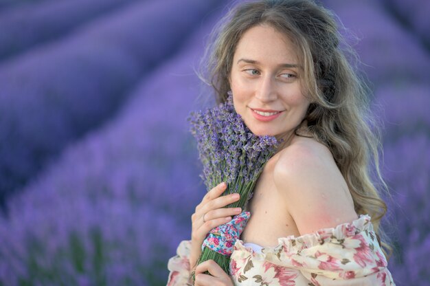 Woman in lavender field at sunset wearing summer dress