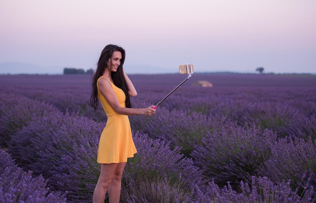 woman in lavender field taking selfie with smartphone