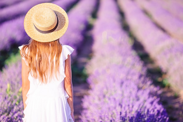 Donna in campo di fiori di lavanda in abito bianco e cappello