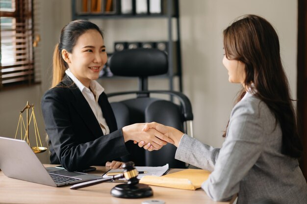 Photo woman lawyer hand and women client shaking hand collaborate on working agreements with contract documents at the modern office