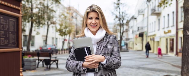 Photo a woman lawyer with a laptop in her hands on the background of the city panorama with a smile looks