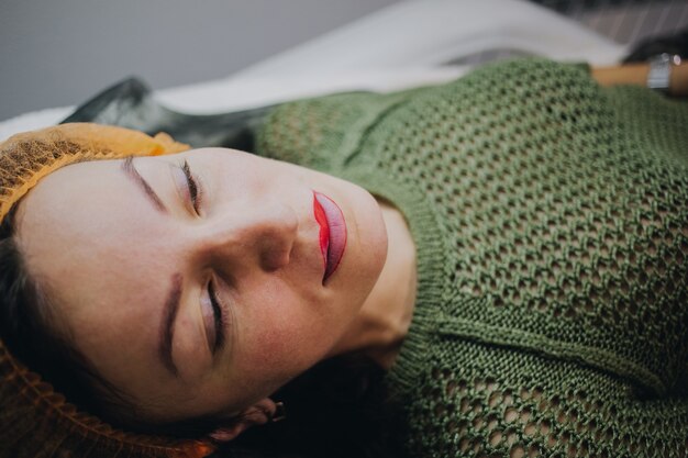 Woman lay at beauty salon for lips permanent makeup procedure