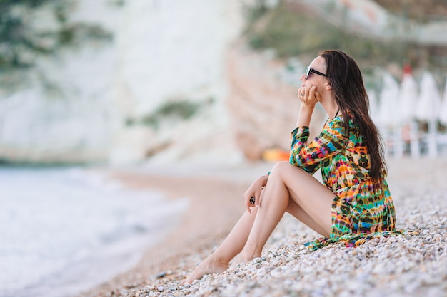 Donna che pone sulla spiaggia godendo le vacanze estive guardando il mare