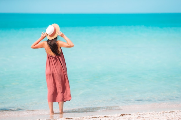 Donna che pone sulla spiaggia godendo le vacanze estive guardando il mare