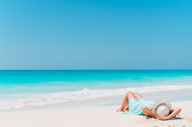 Donna che pone sulla spiaggia godendo le vacanze estive guardando il mare