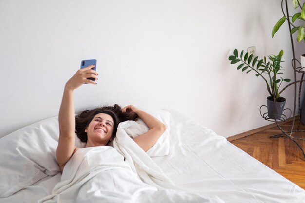 Premium Photo Woman Laying In Bed Taking Selfie On The Phone 