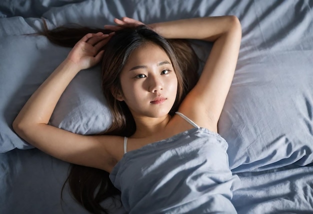 a woman laying on a bed with a gray blanket